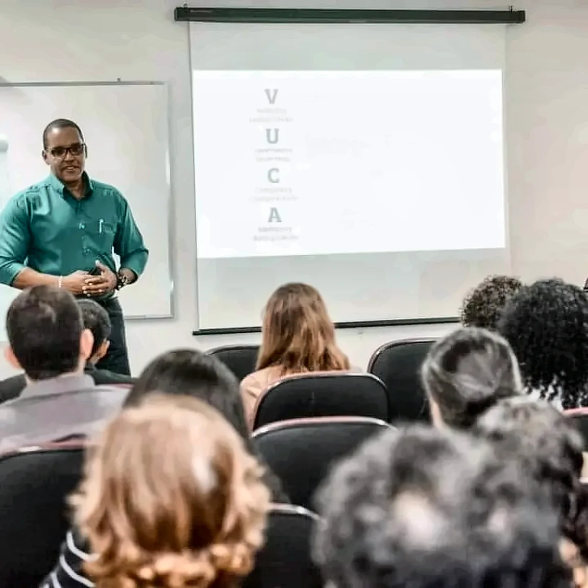 Luetil Neto apresenta diante de uma tela com o tema VUCA